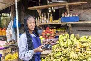 africano mercato donna Tenere un' pos dispositivo foto