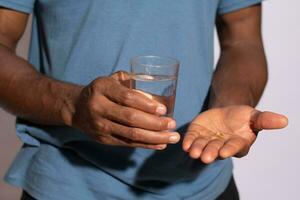 persona Tenere il suo farmaci e un' bicchiere di acqua vicino su foto