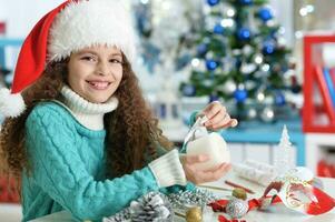 contento ragazza nel Santa cappello seduta con Natale presente foto