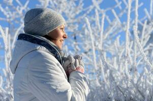 contento giovane donna in posa nel nevoso inverno parco foto