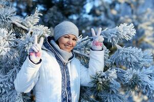 contento giovane donna in posa nel nevoso inverno parco foto