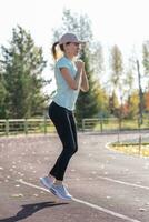 un' giovane bellissimo donna nel abbigliamento sportivo giochi gli sport a un' Locale stadio foto