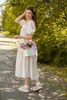 bellissimo ragazza con fiori, nel un' vestire, bicchieri e scarpe da ginnastica. foto