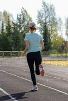 un' giovane bellissimo donna nel abbigliamento sportivo giochi gli sport a un' Locale stadio foto