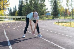 un' giovane bellissimo donna nel abbigliamento sportivo giochi gli sport a un' Locale stadio foto