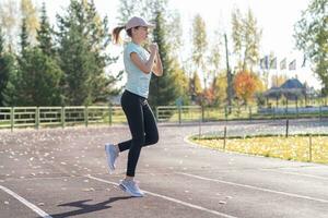 un' giovane bellissimo donna nel abbigliamento sportivo giochi gli sport a un' Locale stadio foto