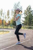 un' giovane bellissimo donna nel abbigliamento sportivo giochi gli sport a un' Locale stadio foto