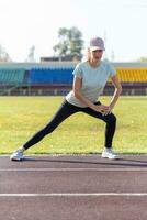 un' giovane bellissimo donna nel abbigliamento sportivo giochi gli sport a un' Locale stadio foto