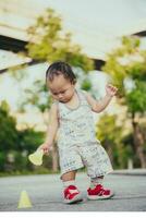 poco bambino piccolo ragazzo è giocando con giallo cono marcatore. bambino è in piedi Tenere marcatore pratica cono. 1 anno vecchio figlio è giocando su terreno di gioco al di fuori il Casa. verticale fotografie. foto