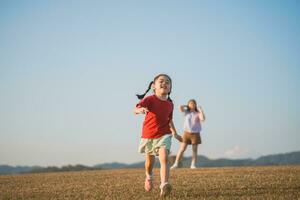 contento bambino asiatico ragazza sorridente. poco ragazza in esecuzione e sorridente a tramonto contento bambino ragazza sorridente. poco bambino in esecuzione a tramonto. carino bambino in esecuzione a terreno di gioco giardino. foto