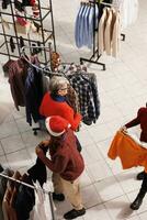 persone fabbricazione preparazioni per Natale vigilia attività e dogana, i clienti guardare per di stagione regali e festivo abbigliamento. gli acquirenti a boutique Acquista merce nel dicembre. foto