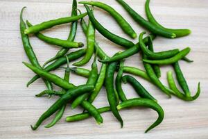 fresco verde chili Pepe su pianura di legno tavolo, verde essenziale verdure per tutti essenziale Alimenti, Visualizza di non pelati verdure con pianura sfondo foto