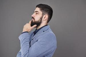 ritratto di uomo libero professionista con barba in giacca in piedi su sfondo grigio foto