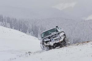 suv cavalca su una montagna invernale guidando rischio di neve e ghiaccio, alla deriva foto