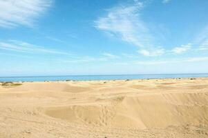 un' sabbioso spiaggia con blu cielo e blu acqua foto