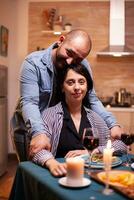 coppia festeggiare relazione guardare a webcam nel cucina. sposato persone speciale tenero momenti, godendo il pasto a candela luci celebrazione. foto