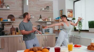 sposato coppia avendo divertimento danza nel cucina durante prima colazione. spensierato marito e moglie ridendo, cantando, danza ascoltando riflettendo, vivente contento e preoccupazione gratuito. positivo le persone. foto