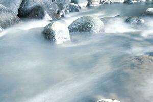 vicino su di acqua fluente al di sopra di ciottolo nel fiume foto