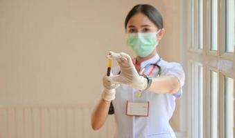 infermiera che indossa guanti con una provetta per analisi del sangue anteriore, concetti che esaminano l'infezione da virus covid-19. foto