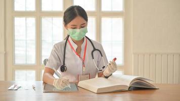 le infermiere indossano guanti e maschera usano il tablet per registrare i risultati degli esami del sangue per le persone infette dal virus covid-19. foto