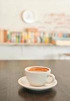 tazza da caffè bianca sul tavolo di legno, sfondo, libreria.