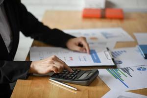colpo ritagliato del personale contabile sta usando calcolatrici e grafici per pagare le tasse annuali. foto