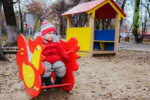 poco ragazzo è giocando su il terreno di gioco nel il parco foto