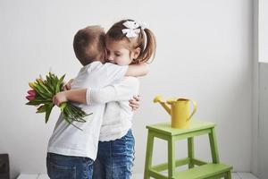 bel ragazzo e ragazza con tulipani con abbraccio. festa della mamma, 8 marzo, tanti auguri foto