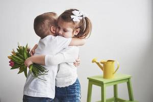 bel ragazzo e ragazza con tulipani con abbraccio. festa della mamma, 8 marzo, tanti auguri foto