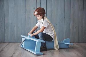 bambino felice in cappello pilota che gioca con l'aeroplano di legno contro. infanzia. fantasia, immaginazione. vacanza