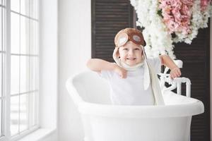 bambino felice in cappello pilota che gioca in bagno. infanzia. fantasia, immaginazione. foto