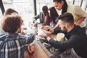 gruppo di amici multietnici creativi seduti al tavolo di legno. persone che si divertono mentre giocano a giochi da tavolo foto