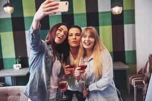 foto che presenta un gruppo felice di amici con vino rosso che si fa selfie