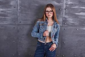 moda, abbigliamento, concetto di persone. attraente giovane donna sexy con giacca di jeans. la ragazza sta posando in studio foto