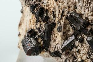 macro minerale pietra schorl, nero tormalina su il feldspato su un' bianca sfondo foto