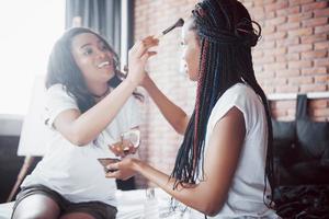 due belle ragazze africane in pigiameria sorridenti sedute sul letto a casa si sono svegliate la mattina in una giornata di sole. foto