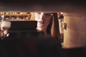 una giovane studentessa sta cercando il libro giusto sugli scaffali della vecchia biblioteca universitaria