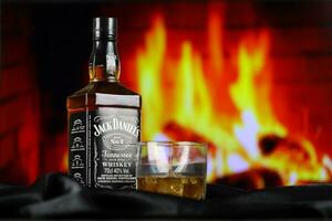 kiev, Ucraina - Maggio 4, 2022 Jack daniel originale alcool bottiglia su di legno tavolo con rosso camino foto