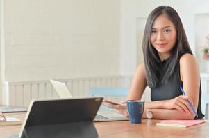 un ritratto di una bella donna d'affari asiatica con un laptop seduto nel suo comodo ufficio.
