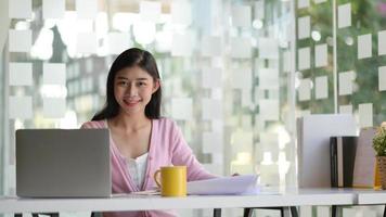 una giovane studentessa con laptop e caffè, sta lavorando a un progetto per laurearsi. foto