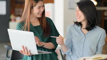 le giovani donne d'affari usano il laptop per discutere insieme del progetto in un ufficio moderno con buone emozioni. foto