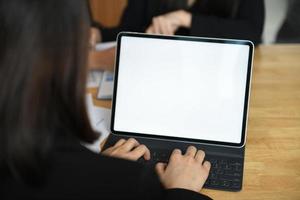 foto ritagliata di una dipendente che digita una tastiera su un laptop con uno schermo bianco vuoto.
