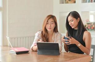 due giovani studentesse con caffè stanno usando un laptop per studiare online a casa nel semestre estivo. foto