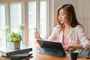 un ritratto di una studentessa asiatica sta usando uno smartphone e un laptop per prepararsi alla laurea. foto