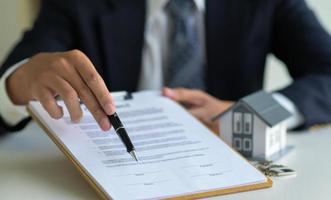 primo piano del broker di casa che punta la penna sul documento che firma il contratto di acquisto della casa.