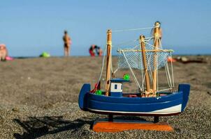 un' giocattolo barca su il spiaggia foto