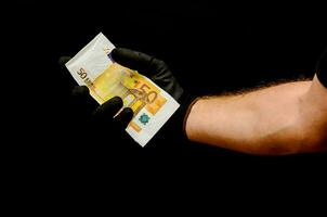 un' persona nel nero guanti Tenere un' banconota foto
