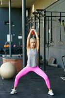 in forma giovane donna fare squat esercizi con kettlebell nel Palestra foto