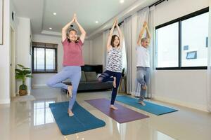 anziano asiatico coppia e figlia siamo fare allenarsi a casa nel in piedi yoga equilibratura posa per rilassante esercizio e Sambuco salutare concetto foto