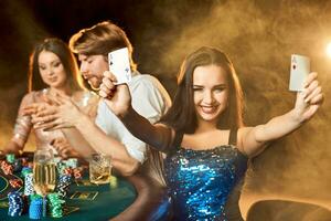 gruppo di un elegante persone giocando poker a il gioco d'azzardo Casa. messa a fuoco su un' emotivo brunetta nel un' blu brillante vestito foto